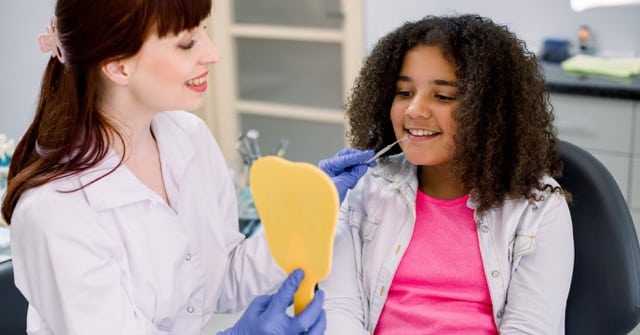 Orthodontist in Austin, TX showing early treatment results to young patient with mirror