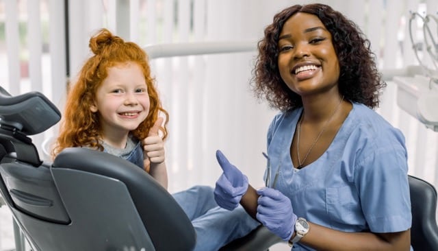 Orthodontist in Austin, TX with smiling child giving thumbs up after checkup